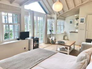 a bedroom with a bed and a living room with windows at Coastal Chic waterfront studio in Kinsale