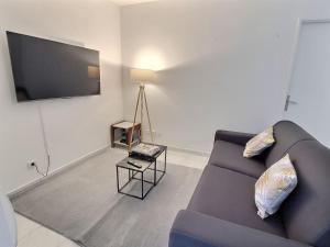 a living room with a purple couch and a television at Le Cosy Magny *Paris*Disney*Wifi in Magny-le-Hongre