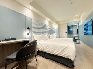 1 dormitorio con 1 cama grande y 1 silla en 逢甲享沃行旅 Joie de Inn en Taichung