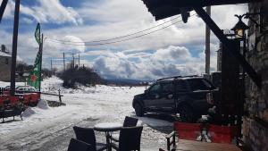 un'auto parcheggiata fuori da un edificio nella neve di Patriko Mountain Chalet a Palaios Agios Athanasios