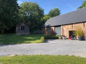 une ancienne grange en briques avec une table et des chaises à l'extérieur dans l'établissement GrIsa'Home, à Aisonville-et-Bernoville