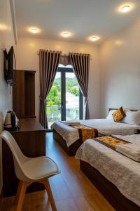 a hotel room with two beds and a chair and a window at Hotel Mỹ Vy in Tánh Linh