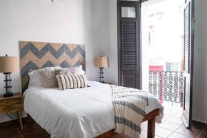 - une chambre dotée d'un grand lit avec des draps et des oreillers blancs dans l'établissement Historic Apt w/ 3BR Near La Fortaleza OSJ, à San Juan