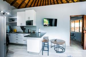 a kitchen with white cabinets and a table and stools at Wildevy at Benlize in Hartbeespoort