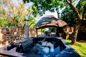 an outdoor swimming pool with a thatch roof at Wildevy at Benlize in Hartbeespoort