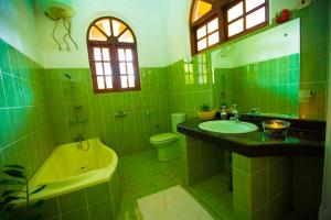 a green bathroom with a tub sink and a toilet at rockwood vila in Kandy