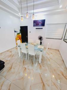 uma sala de jantar com uma mesa de vidro e cadeiras brancas em Domicile Houéyiho 2 em Cotonou