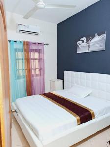 um quarto com uma cama branca e uma parede azul em Domicile Houéyiho 2 em Cotonou