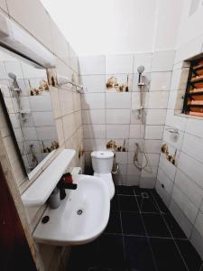 uma casa de banho com um lavatório branco e um WC. em Domicile Houéyiho 2 em Cotonou