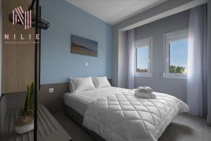 a bedroom with a white bed and two windows at Ouranos, Nilie Hospitality MGMT in Nikiti