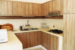 una cocina con armarios de madera y fregadero en Villa Oberoi 2 bedrooms, en Seminyak