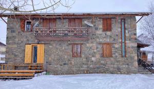 古道里的住宿－Snowpeak Chalet Gudauri，一座石头建筑,设有黄色的门和阳台
