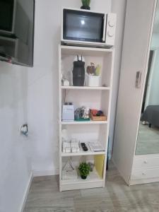 un estante de libros blanco con una TV encima en ESTUDIO en TORREMOLINOS, PLAZA DE ANDALUCIA, en Torremolinos