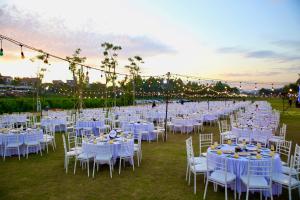 a long row of tables and chairs with white tables and chairs at Miyabi Wyndham Thanh Thuỷ in Phú Thọ