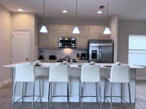 uma cozinha com cadeiras brancas e uma grande ilha de cozinha em Balmoral Resort-207AL home em Haines City
