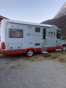 una caravana blanca y roja estacionada junto a una montaña en Aurora bobil, 
