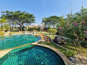 a swimming pool in a resort with trees and flowers at Phoo Na Resort in Chiang Mai