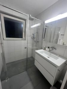 a white bathroom with a sink and a shower at Quickmove Paffikon in Pfäffikon