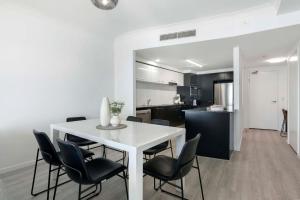 a kitchen and dining room with a white table and chairs at 3 Bedroom Apartment with Ocean Views in Central Location - Chevron Renaissance - Wow Stay in Gold Coast