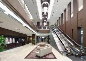 a lobby with an escalator in a building at Palace Hotel Omiya in Saitama