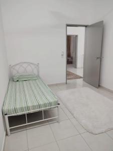 Cama en habitación blanca con alfombra en Umi Homestay, Laman Haris, en Bandar Puncak Alam