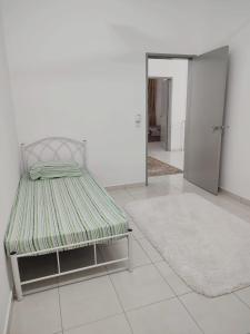 ein Bett in einem weißen Zimmer mit einem Teppich in der Unterkunft Umi Homestay, Laman Haris in Bandar Puncak Alam