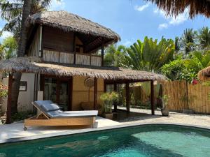 a resort with a pool and a chair and a house at Villa Maiya in Gili Islands