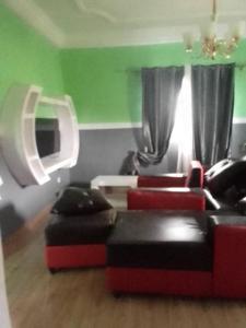 una sala de estar con muebles rojos y negros y paredes verdes. en NGOME Lounge, 