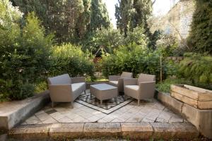 um pátio com cadeiras e uma mesa num jardim em Historic 4-Bedroom Gem with Private Garden, Steps from Old City & Mamila Complex em Jerusalém