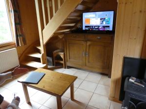 a living room with a staircase and a television at Chalet Beaujon Chapelle-des-Bois in Chapelle-des-Bois