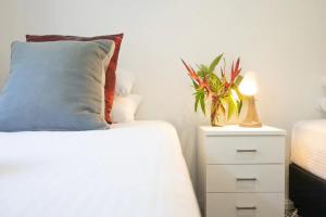 a bed with a pillow and a night stand with a plant at Byron Lakeside Holiday Apartments in Byron Bay