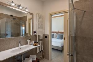 a bathroom with a sink and a mirror and a bed at Sporting Hotel San Felice in Illasi