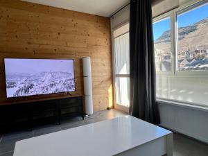 a living room with a flat screen tv next to a window at L Altitude 3 pièces centre station moderne et rénové in Les Deux Alpes