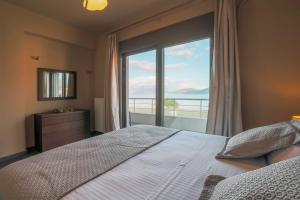 a bedroom with a bed and a large window at Malena in Karavomylos +21 photos