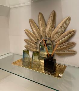 une plaque en bronze avec des verres et une plante sur une étagère dans l'établissement RIAD DAR NAOMI, à Marrakech