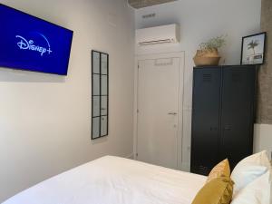 a bedroom with a bed and a tv on the wall at La Reina Beach rooms in Valencia
