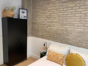 1 dormitorio con pared de ladrillo junto a la cama en La Reina Beach rooms, en Valencia