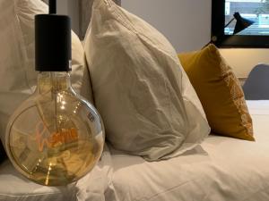 Una botella en la parte superior de una cama con almohadas en La Reina Beach rooms, en Valencia