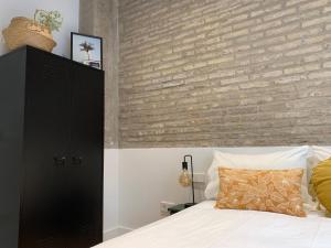 バレンシアにあるLa Reina Beach roomsのレンガの壁とベッドが備わるベッドルーム1室が備わります。
