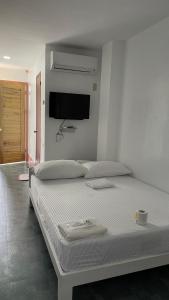 ein weißes Schlafzimmer mit einem Bett und einem Flachbild-TV in der Unterkunft Langoyon Beach Resort 