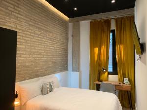 une chambre avec un lit blanc et un mur de briques dans l'établissement La Reina Beach rooms, à Valence