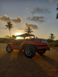 un jeep rojo estacionado en un camino de tierra con palmeras en Pousada Refúgio dos Milagres, en São Miguel dos Milagres