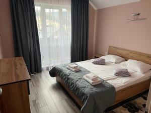 1 dormitorio con 1 cama con 2 toallas en Guest House Zatyshnyi Dvir en Bukovel