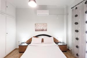 1 dormitorio con 1 cama blanca grande y paredes blancas en Cozy Cityscape Apartment in Athens en Athens