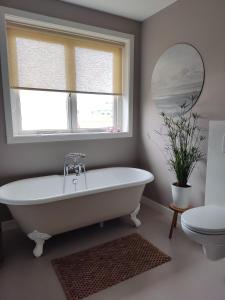 a white bath tub in a bathroom with a window at Sfeervolle woning dichtbij centrum Deventer in Deventer