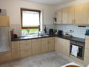 a kitchen with wooden cabinets and a sink and a window at Ferienwohnung Hilderser Auszeit in Hilders