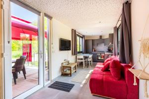 Tinyhouses - Domain "La vallée des Prés" في Bande: غرفة معيشة مع أريكة حمراء ومطبخ