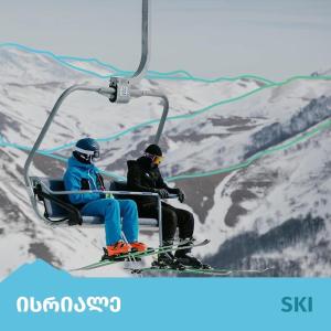 zwei Personen reiten einen Skilift auf einem schneebedeckten Berg in der Unterkunft Kokhta - Mitarbi Apartment , Bakuriani in Bakuriani