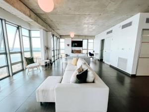 uma sala de estar com um sofá branco e algumas janelas em Luxurious SubPh Apt Atlantis W/ Ocean View & PRK em San Juan