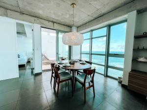 a dining room with a table and chairs and the ocean at Luxurious SubPh Apt Atlantis W/ Ocean View & PRK in San Juan